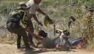 Una migrante es arrastrada para librar un alambre de púas, a lo largo del Río Grande, ayer.