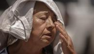 Una mujer de la tercera edad cubre su cabeza y seca su sudor ante el fuerte calor