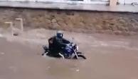 Un hombre se aferra a motocicleta, que es arrastrada por una inundación en Acapulco, donde este lunes impactó 'Max'