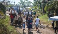 Habitantes de Llano Largo, Acapulco, caminan a sus hogares, tras recibir su paquete de enseres domésticos.