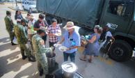 Elementos del Ejército entregan platos de guisados calientes para los afectados.