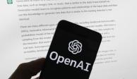 El logotipo de OpenAI se ve en un teléfono móvil frente a una pantalla de computadora que muestra el resultado de ChatGPT.