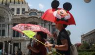 Personas se protegen del sol con sombrillas, ayer en la Ciudad de México.