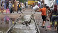 Migrantes en un campamento de la colonia Vallejo sacan el agua acumulada por las fuertes lluvias de los últimos días, el pasado jueves 18 de julio.