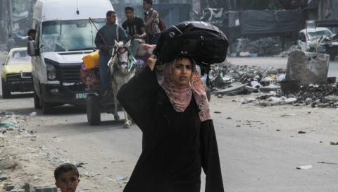 Mujeres y hombres, a pie o en transporte, cargan sus pocas pertenencias para escapar de Rafah, su último refugio.