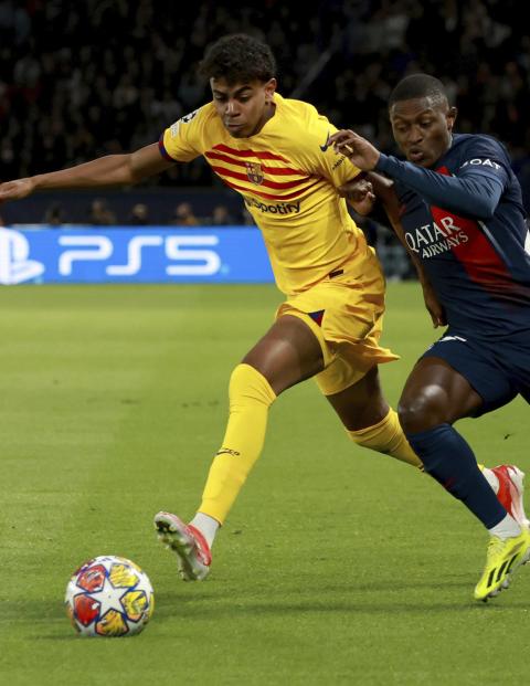 Lamine Yamal lucha por un balón con Nuno Mendes en la ida de cuartos de final de Champions League entre PSG y Barcelona.