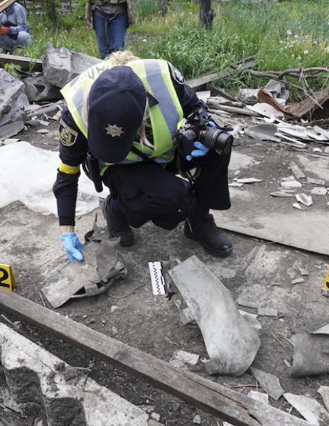 Un oficial de la Policía recaba evidencia de los bombardeos en una aldea de Járkov.