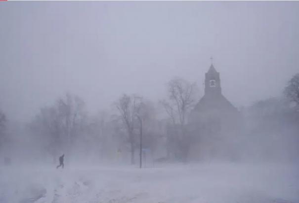 Un peatón con equipo para la nieve avanza por el Colonial Circle, con la silueta de la iglesia episcopaliana de St. John's Grace entre la ventisca, en Buffalo, Nueva York, el sábado 24 de diciembre de 2022