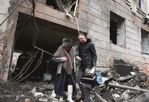 Personal de emergencia ayuda a una ciudadana a salir de un edificio bombardeado en Járkov, ayer.