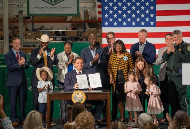 El Gobernador Ron DeSantis muestra la nueva ley firmada, ayer.