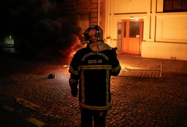 Un bombero francés trabaja para extinguir una moto en llamas durante el quinto día de protestas en Francia.