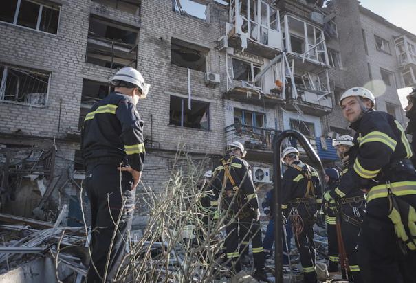 Personal de emergencias y bomberos se preparan para inspeccionar un edificio residencial impactado por un misil, ayer.