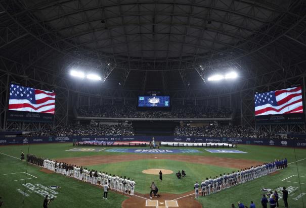 Miembros de los Dodgers y los Padres escuchan el himno nacional antes del partido del día inaugural en Corea del Sur.