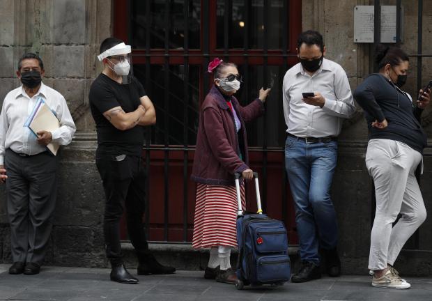 Personas con cubrebocas hacen fila antes de ingresar a un banco el 6 de julio de 2020, en el centro de la Ciudad de México.