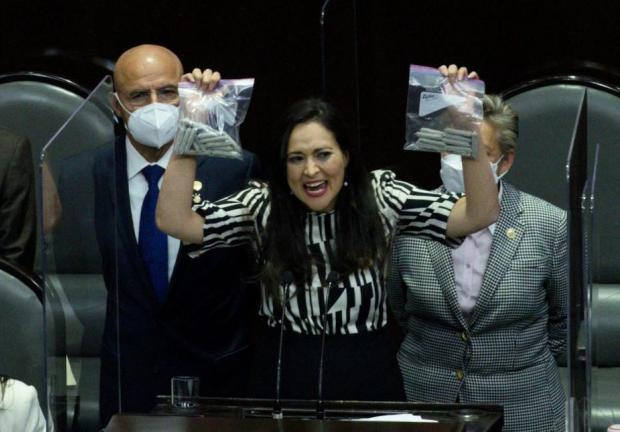 La diputada del PRI, Cynthia López, muestra dos bolsas llenas de "churros" de marihuana.