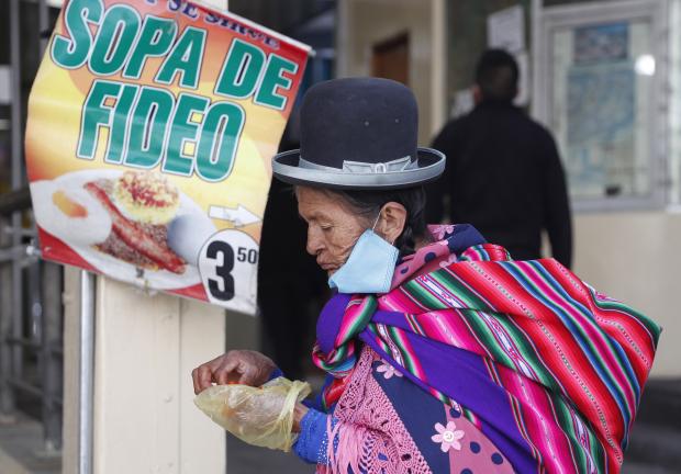 Una mujer come una sopa de fideos en la calle en La Paz, Bolivia, 2 de junio de 2020.