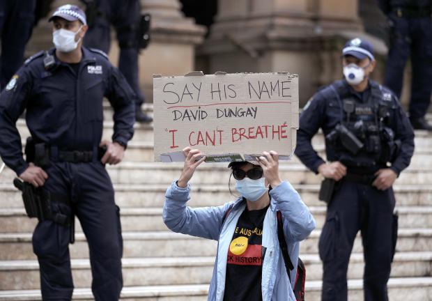 Mujer con pancarta durante protestas contra el racismo en Australia.