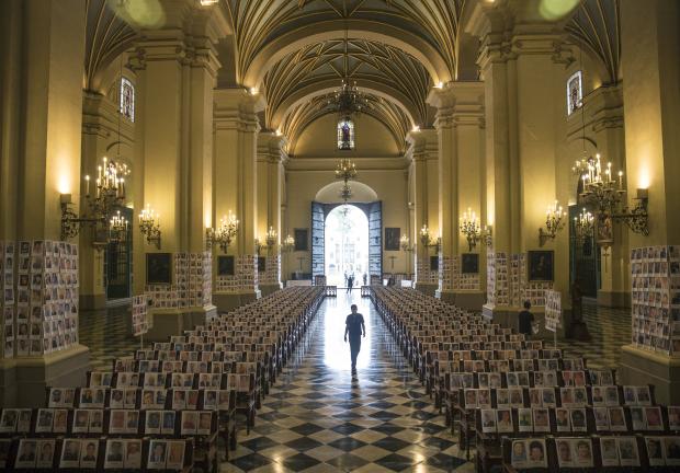 Un hombre camina entre las fotografías en la Catedral de Lima, Perú. 