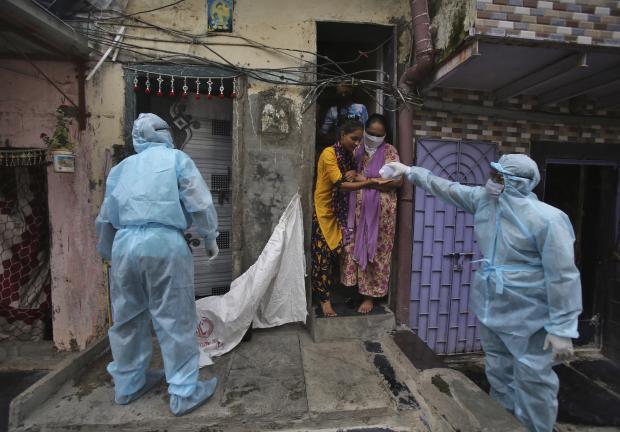 Un trabajador de la salud le da un desinfectante de manos a una niña durante un campamento de control en un barrio pobre en Mumbai, India, el 17 de junio de 2020.