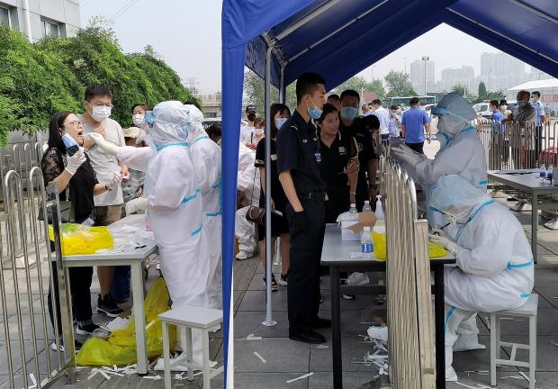 Las personas se forman para hacerse pruebas de ácido nucleico, después de que se confirmaron nuevos casos de enfermedad por coronavirus (COVID-19) en Dalian, provincia de Liaoning, China
