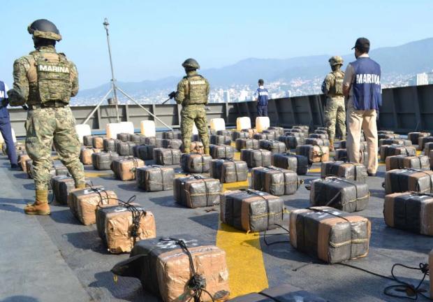 Elementos de la Guardia Costera muestran los bultos de droga y bidones recuperados en el mar.