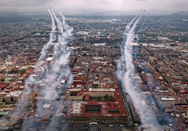 Aviones de la Fuerza Aérea sobrevuelan las calles de la capital, lanzando humo de colores, ayer.