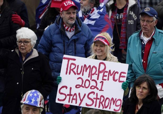 Una mujer sostiene un cartel de Trump-Pence 2021 en un mitin de Trump en el Capitolio estatal, el 6 de enero de 2021.