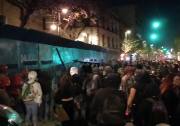 Un grupo de manifestantes continúa golpeando las vallas frente al edificio de la SCJN.