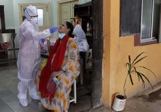 Personal de salud realiza una prueba de COVID-19 a una mujer en un centro médico del gobierno en Mumbai, India