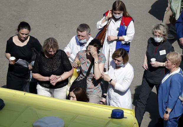 Empleados de salud ayudan a una mujer para que suba a una ambulancia después de un tiroteo en una escuela de Kazán, Rusia, el 11 de mayo de 2021.