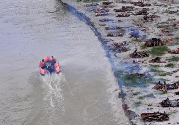 Autoridades de la India creman los cuerpos tras un aumento en el nivel de agua del río Ganges, que dejó al descubierto tumbas de fallecidos por COVID-19.