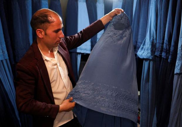 Vendedor afgano muestra un burka en su tienda en un mercado de Kabul, Afganistán.