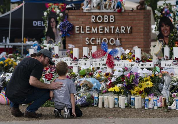 Un hombre y un niño visitaron el monumento instalado en la primaria Robb, en Uvalde, Texas, para honrar a las 21 víctimas del tiroteo del martes, ayer.