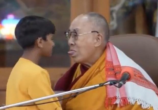 Dalai Lama besa a un niño en la boca.