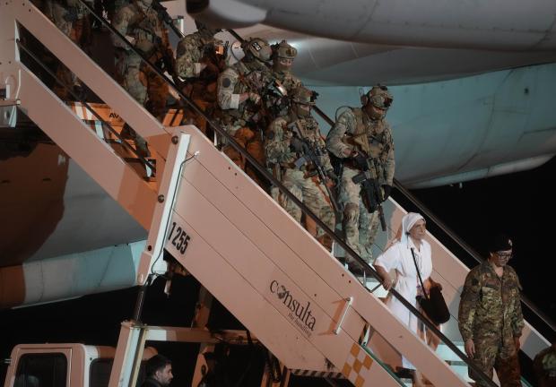 Una monja seguida por soldados del ejército italiano desembarca de un avión de la Fuerza Aérea que transporta ciudadanos italianos evacuados de Sudán aterrizados en el aeropuerto militar de Ciampino en Roma, el lunes 24 de abril de 2023.