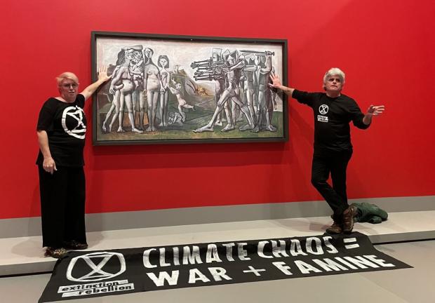 Dos activistas se pegan a la pintura Masacre de Corea de Picasso.