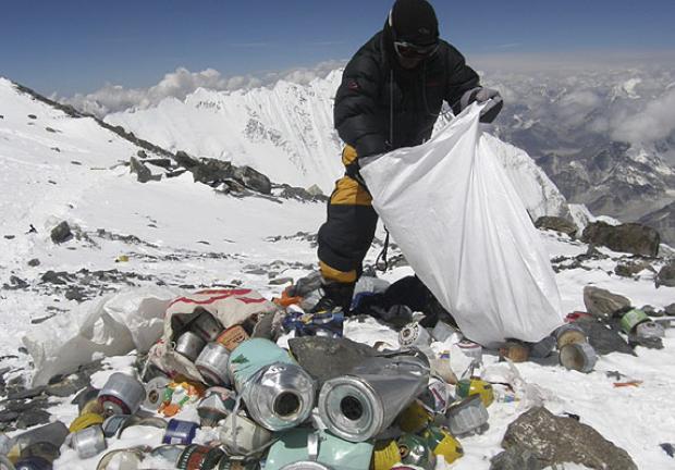 Foto de un alpinista recogiendo plásticos y basura acumulada en el monte Everest, la montaña más alta del mundo.