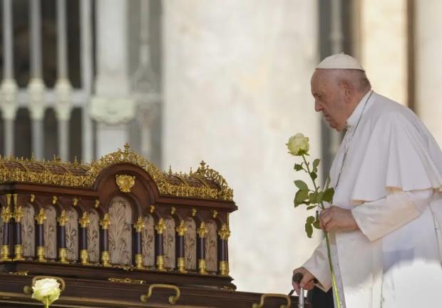 El papa Francisco, con una rosa en la mano, se dispone a rezar ante las reliquias de Santa Teresa del Niño Jesús, patrona universal de las misiones (izquierda), a su llegada a la audiencia nacional en la Plaza de San Pedro, en el Vaticano, el 7 de junio de 2023.