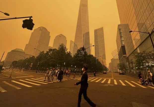 Transeúntes caminan frente al One World Trade Center en medio de la humareda por los incendios forestales de Canadá.