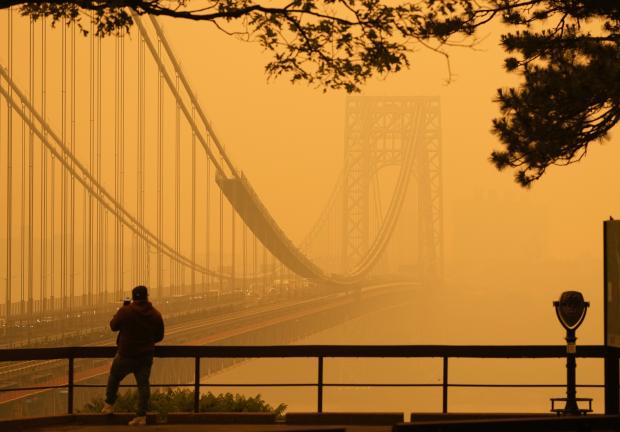 Un hombre conversa por su teléfono en medio de una bruma de humo cerca del puente George Washington, en esta imagen tomada desde Fort lee, Nueva Jersey, el miércoles 7 de junio de 2023.