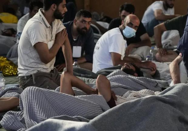 Sobrevivientes de un naufragio descansan en un almacén en el puerto de Kalamata, Grecia, el 14 de junio de 2023.