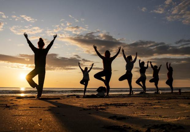 Miembros del grupo Happy Seal Yoga practica en la Bahía Cayton, en Scarborough, al amanecer del Solsticio de Verano el miércoles 21 de junio de 2023.