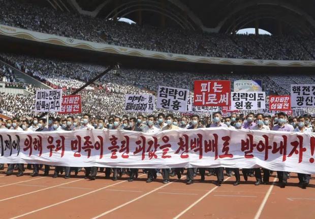 Gente de Pyongyang participa en una manifestación tras una marcha para conmemorar lo que Corea del Norte conoce como "el día de lucha contra el imperialismo estadounidense" en el Estadio del Primero de Mayo en Pyongyang, Corea del Norte, el domingo 25 de junio de 2023. El cartel dice "¡Hagamos que los imperialistas estadounidenses paguen duramente por la sangre derramada por la nación coreana!", "Estados Unidos es el jefe de la guerra y la masacre", "aniquilación inmisericorde", "Estados Unidos es el destructor de la paz", "jefe de agresión", "sangre por sangre" y "maniaco de guerra nuclear"