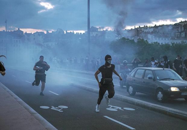 Manifestantes embozados huyen al enfrentar a la policía en la ciudad de Lyon, Francia.