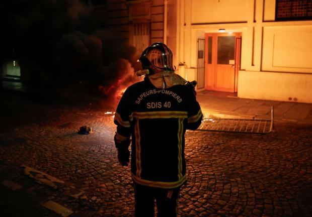 Un bombero francés trabaja para extinguir una moto en llamas durante el quinto día de protestas en Francia.