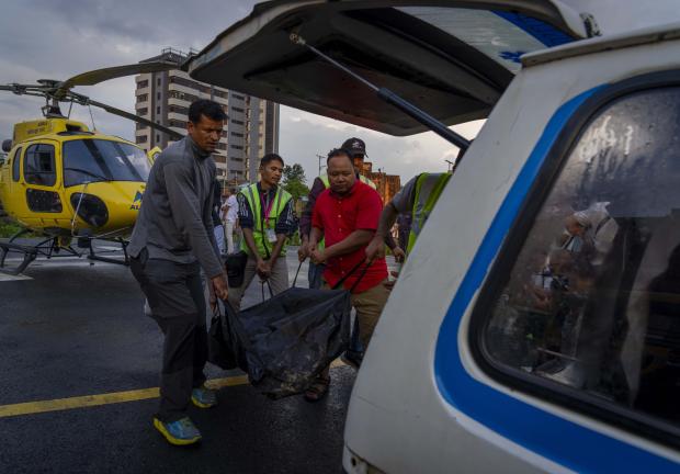 Personas cargan uno de los cuerpos rescatados del helicóptero que se estrelló este martes cerca del Monte Everest.
