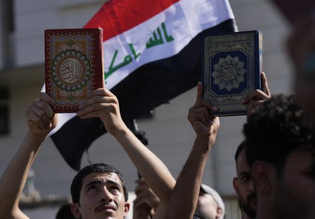 Simpatizantes del sacerdote chií Muqtada al-Sadr levantan el Corán, el libro sagrado para los musulmanes, durante una manifestación frente a la embajada sueca, el 30 de junio de 2023, en Bagdad, en respuesta a la quema del Corán en Suecia.
