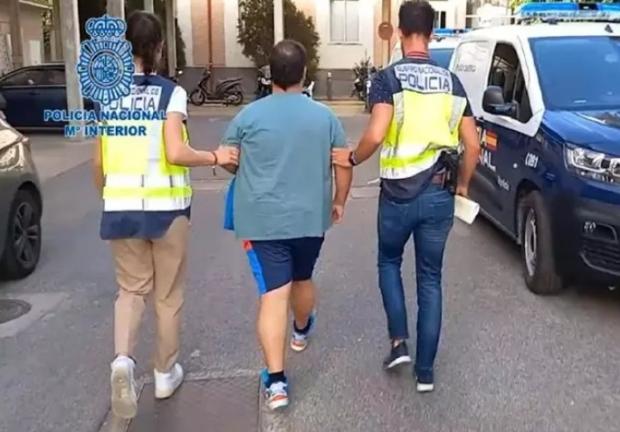 El entrenador de fútbol detenido en Sevilla es conducido por agentes al vehículo de la Policía Nacional de España