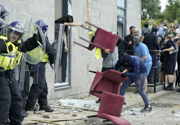 Manifestantes lanzan sillas a oficiales de policía durante las protestas en Reino Unido.