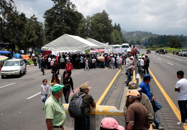 Turistas y habitantes optaron por caminar debido al bloqueo que pobladores de Santa Rita Tlahuapan mantuvieron en la autopista México-Puebla.